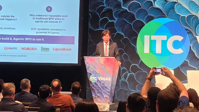 A presenter at the podium beside a slide asking why enterprises outsource repeatable work to traditional BPO when AI agents can execute it.